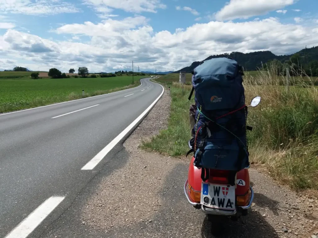 Rote Vespa mit Tourengepäck auf der Landstraße